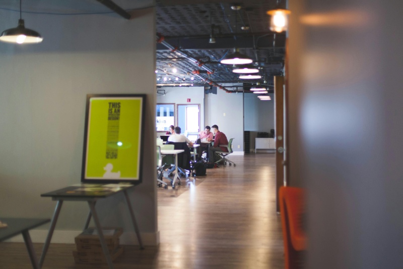 Office employees working under low-glare panel and linear lighting while viewing monitors and paperwork in a modern workspace